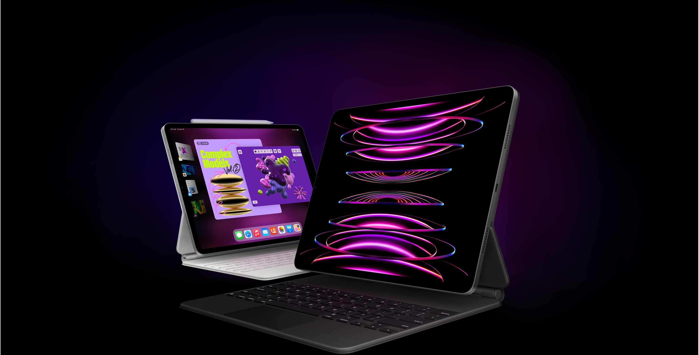 iPad Pro s bílým Magic Keyboardem a Apple Pencilem plus Stage Managerem na obrazovce je umístěný mírně vzadu za dalším iPadem Pro s černým Magic Keyboardem a zobrazenou tapetou.